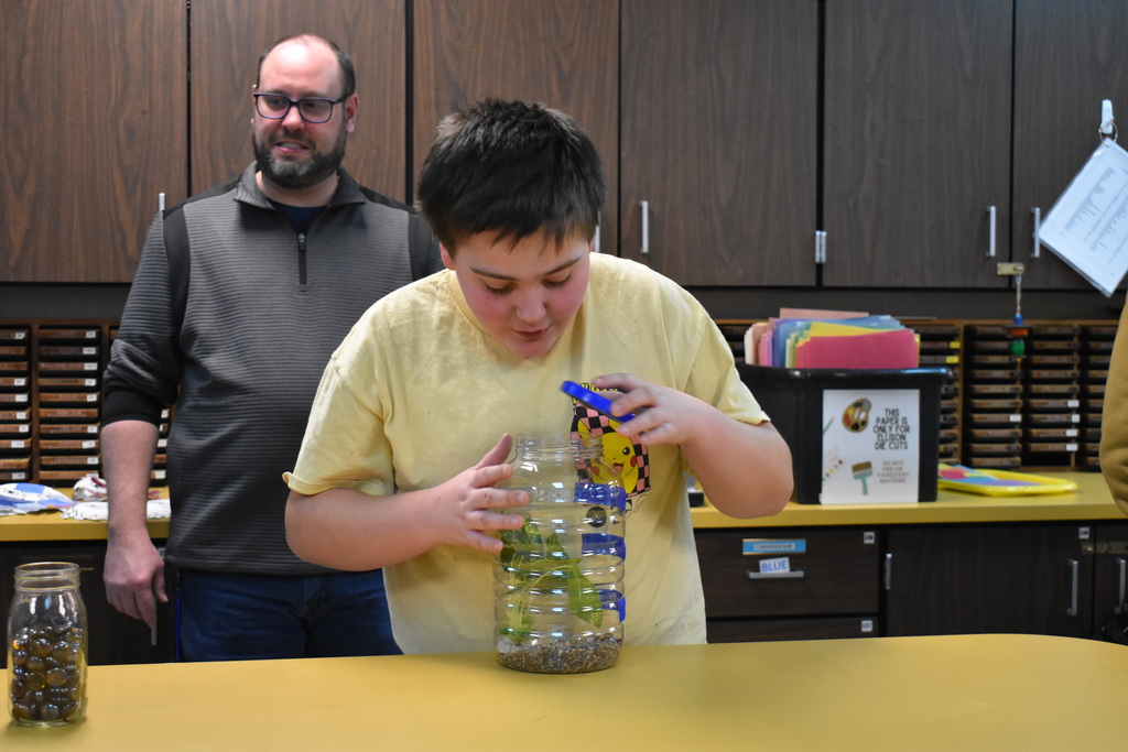 a student inspecting his aquarium he put together