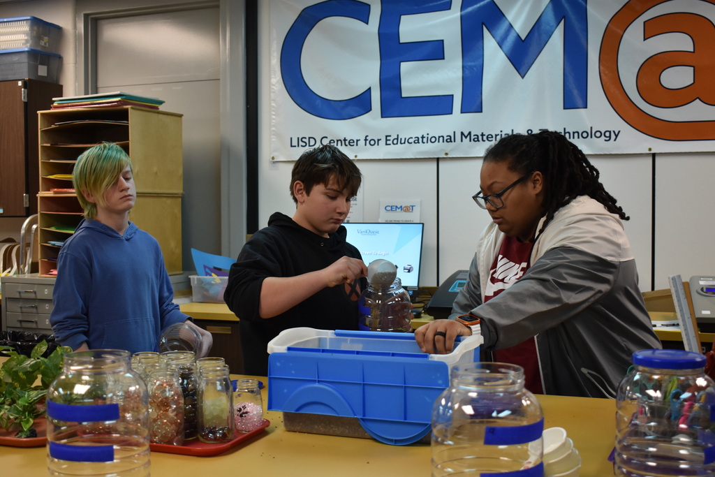 a student placing stone in his aquarium as a teacher assists
