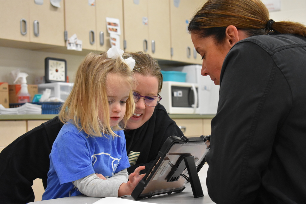 A student and her mom working on an ipad activity with an instructor