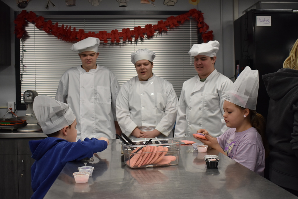 two students decorate cookies while TECH Center students watch