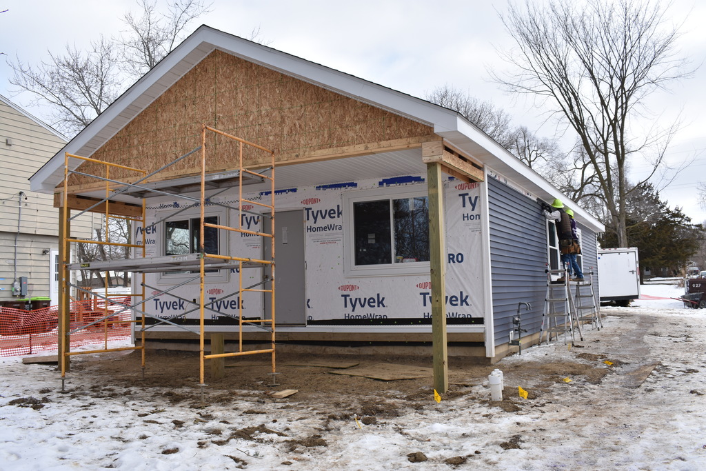 students working on the siding of the house they are building