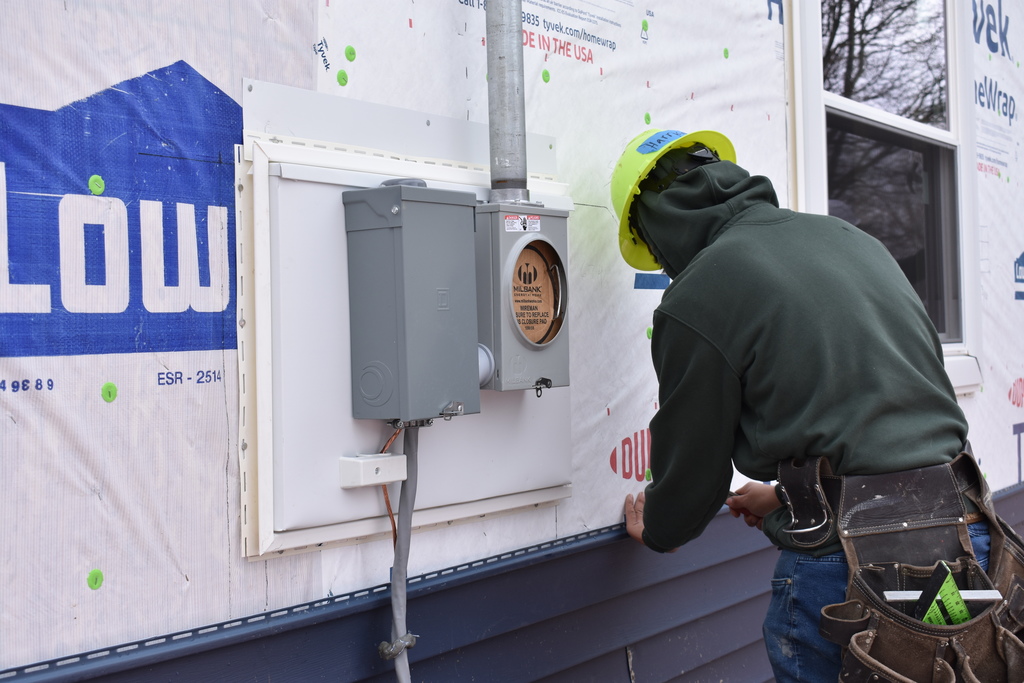 a student working on the siding of the house