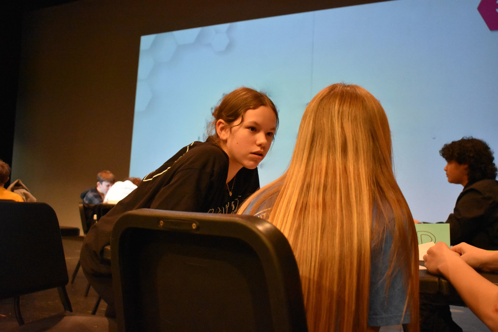 a student leaning in to chat with teammate