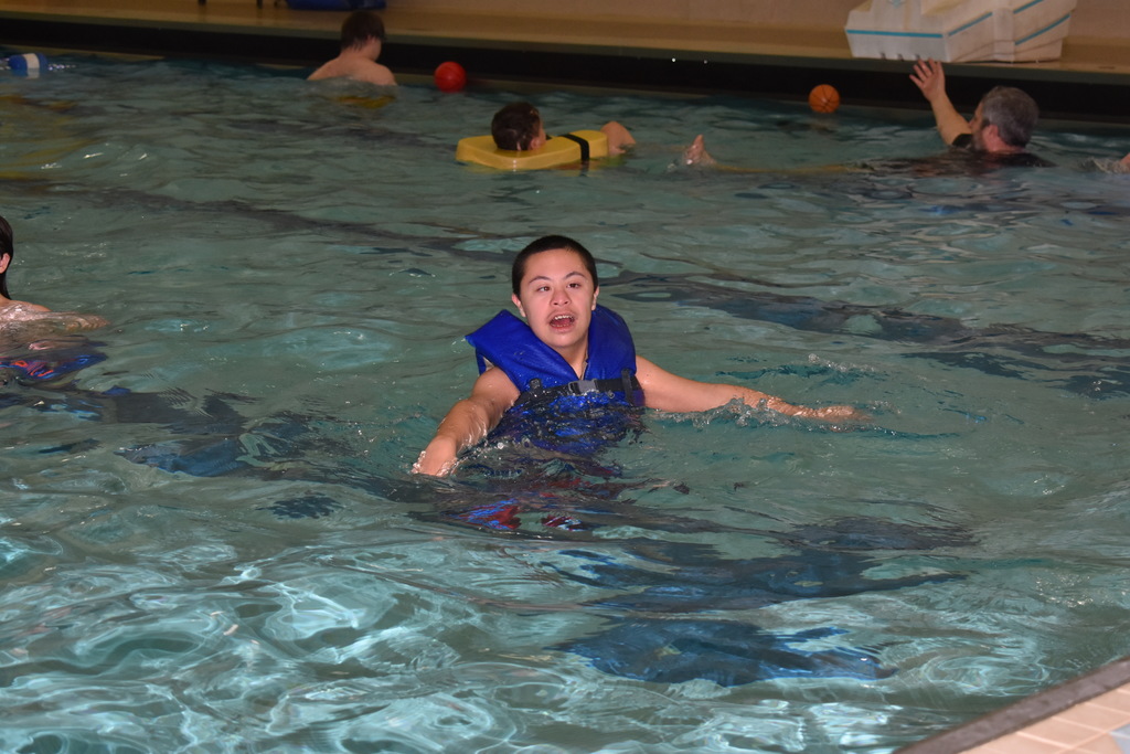 A student smiling and splashing in the pool