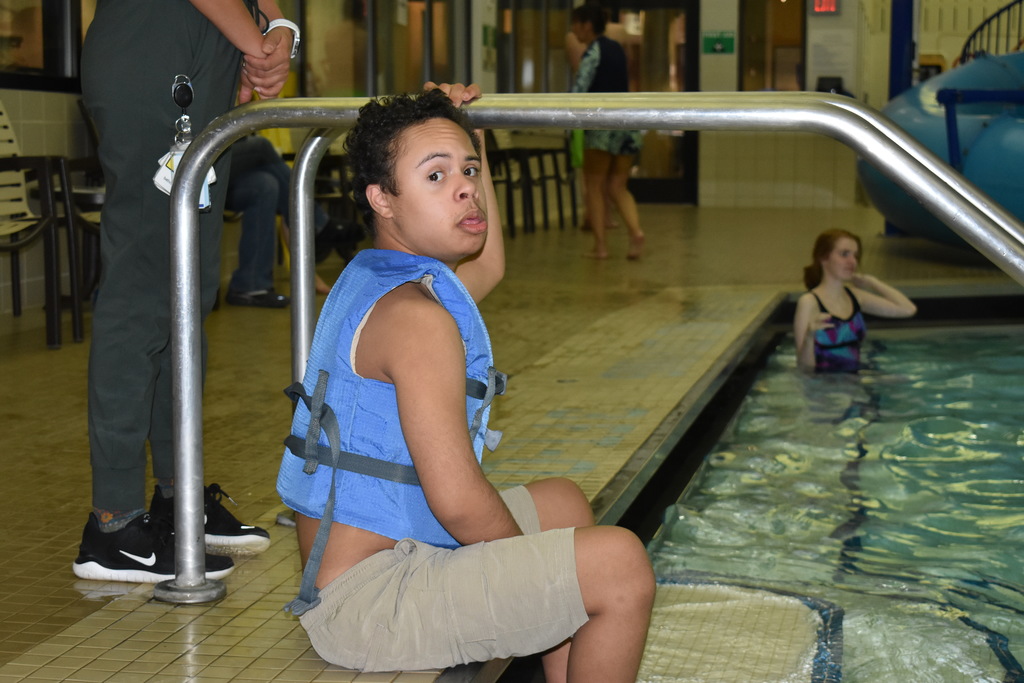 A student looking at the camera while sitting on the steps in the water