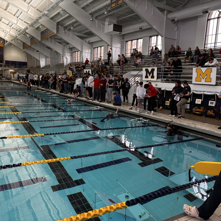 students line up at the edge of the pool to maneuver their robots in water