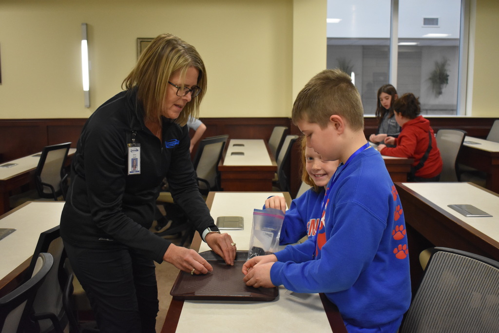 A judge helping two students who are creating a lego project