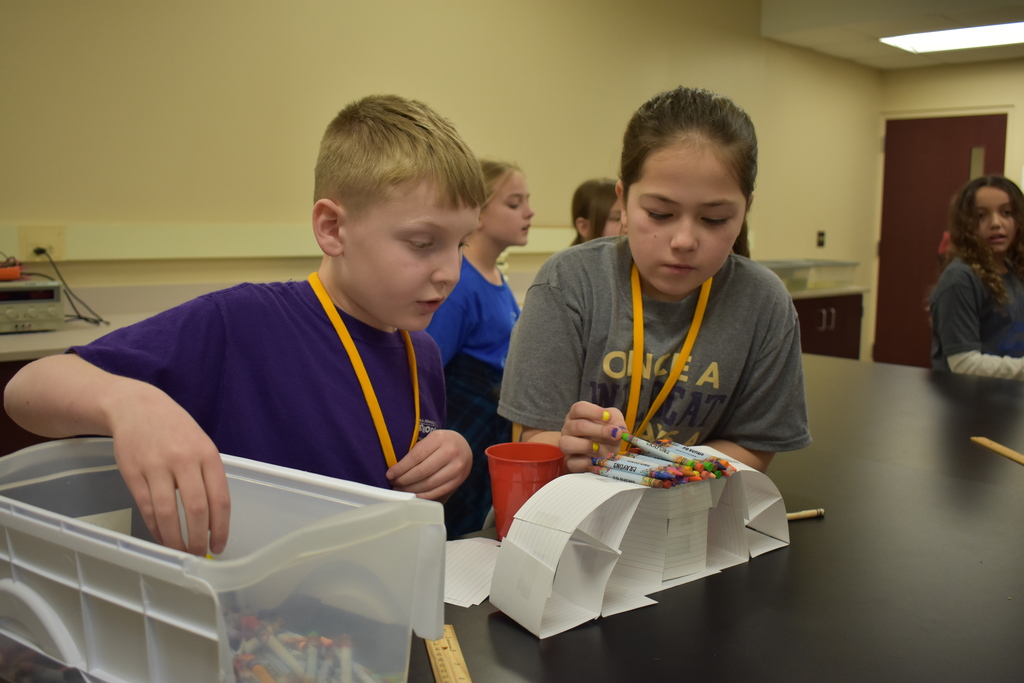 Two students seeing how long their bridge will hold