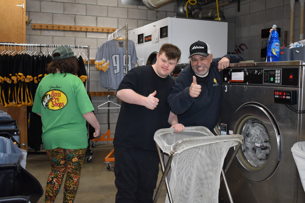 An instructor and student showing us the laundry room and posing with a thumbs up