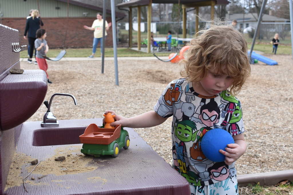 A child playing with a truck and ball