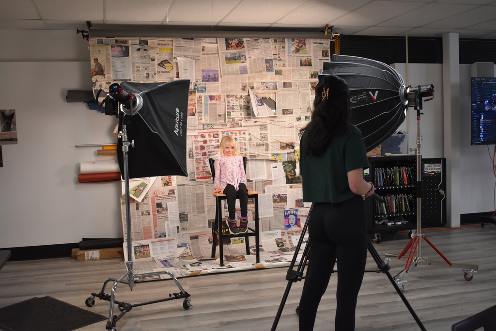 A digital media student taking a photo of a child visiting
