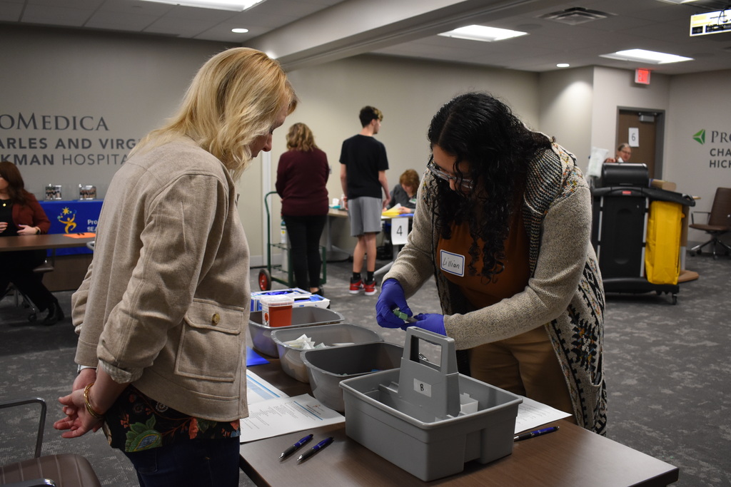 A student organizing medical supplies while an assistant looks on