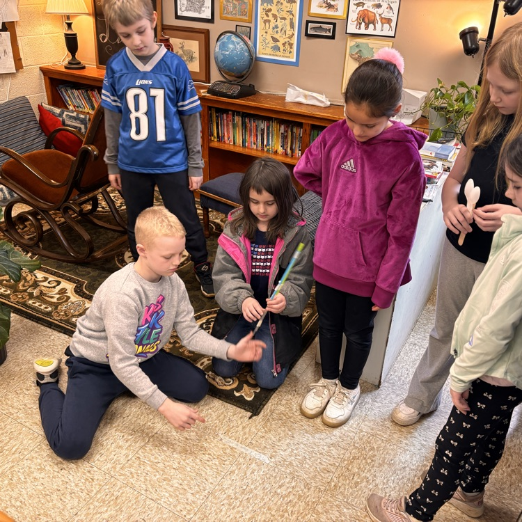 students sit and stand around a catapult for testing