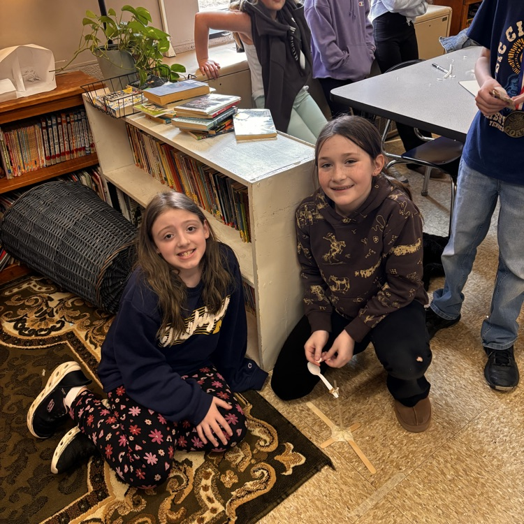 2 girls smile by their catapult