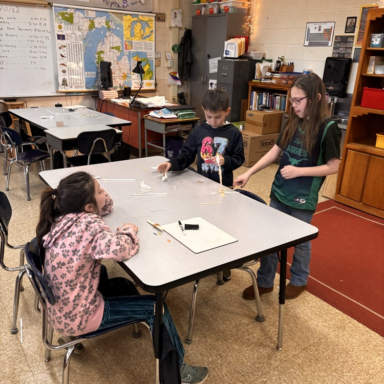 students sit by a table as they creat