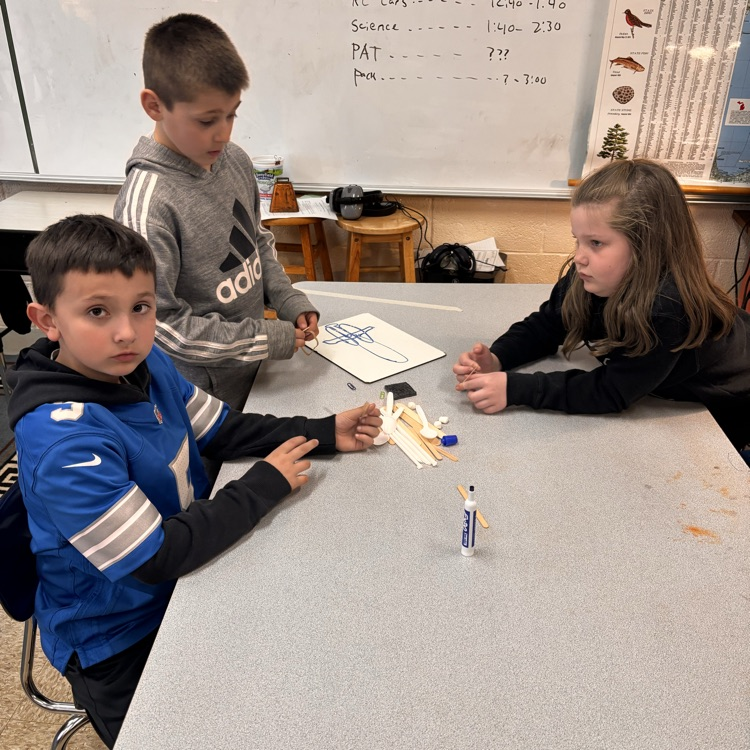 students sit at a table as they create