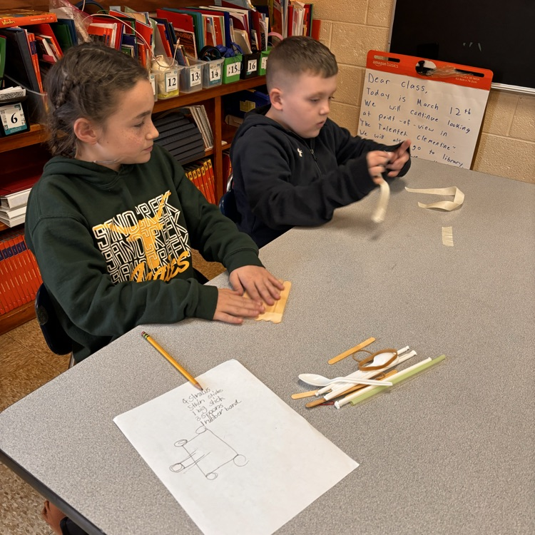 students sit by their table for building