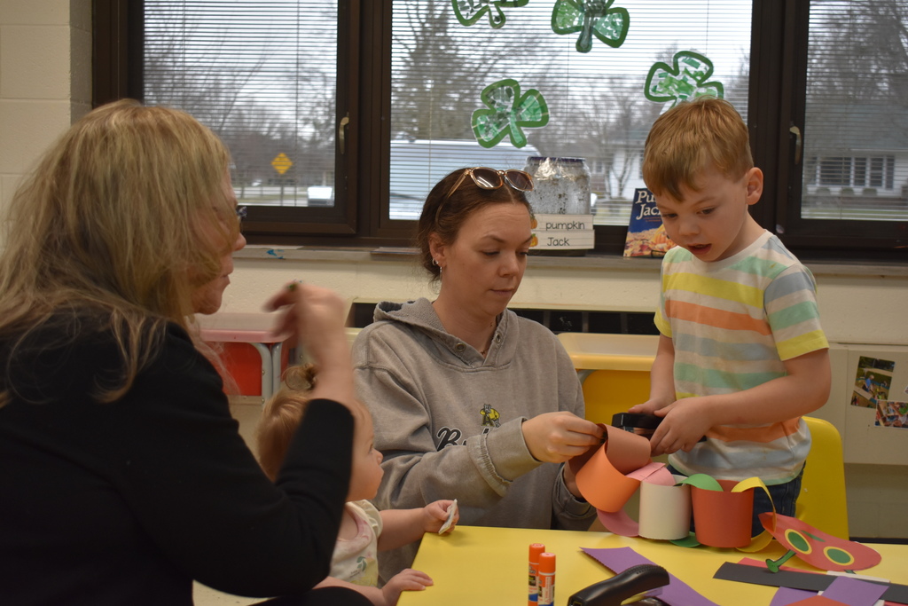 a student working on an art project while a sibling, grandma and mother assist