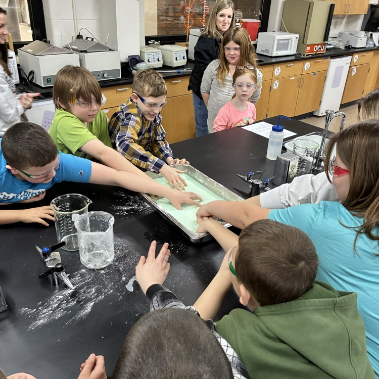 Students grabbing gooey stuff out of a pan in a lab