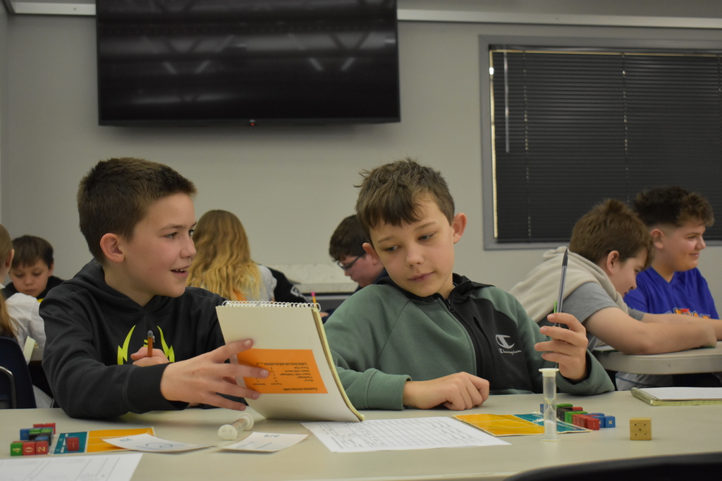 a student showing another student a note in the middle of an equations game