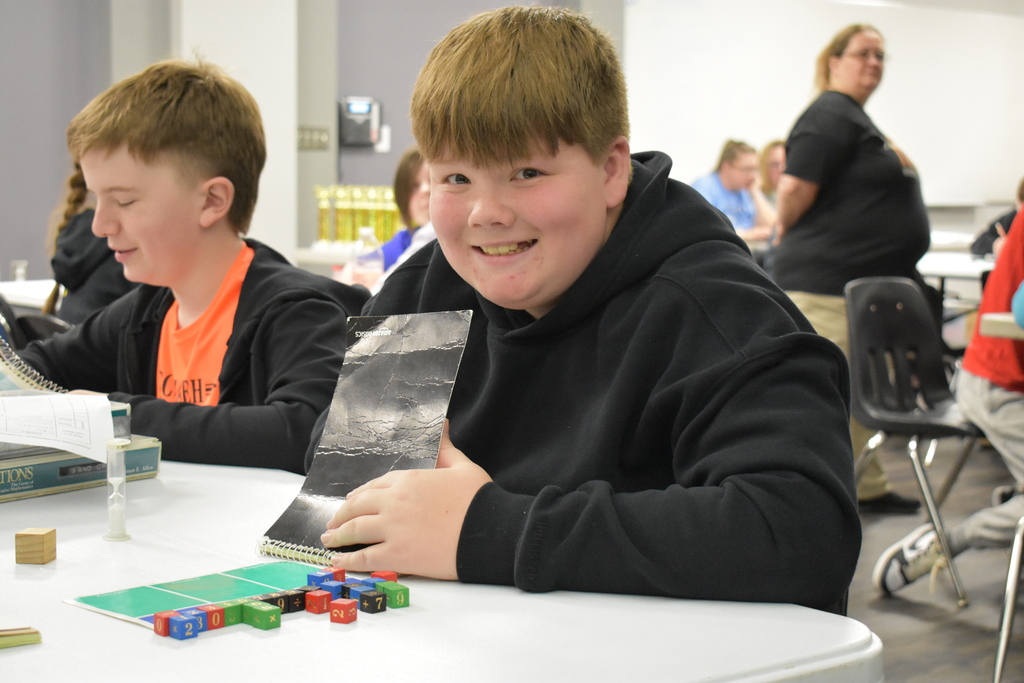 A student smiling for the camera while playing equations