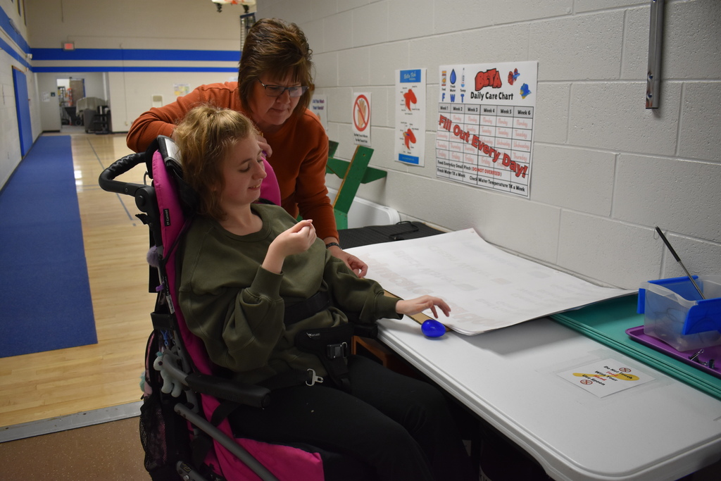A student reaching for her egg as a teacher assists