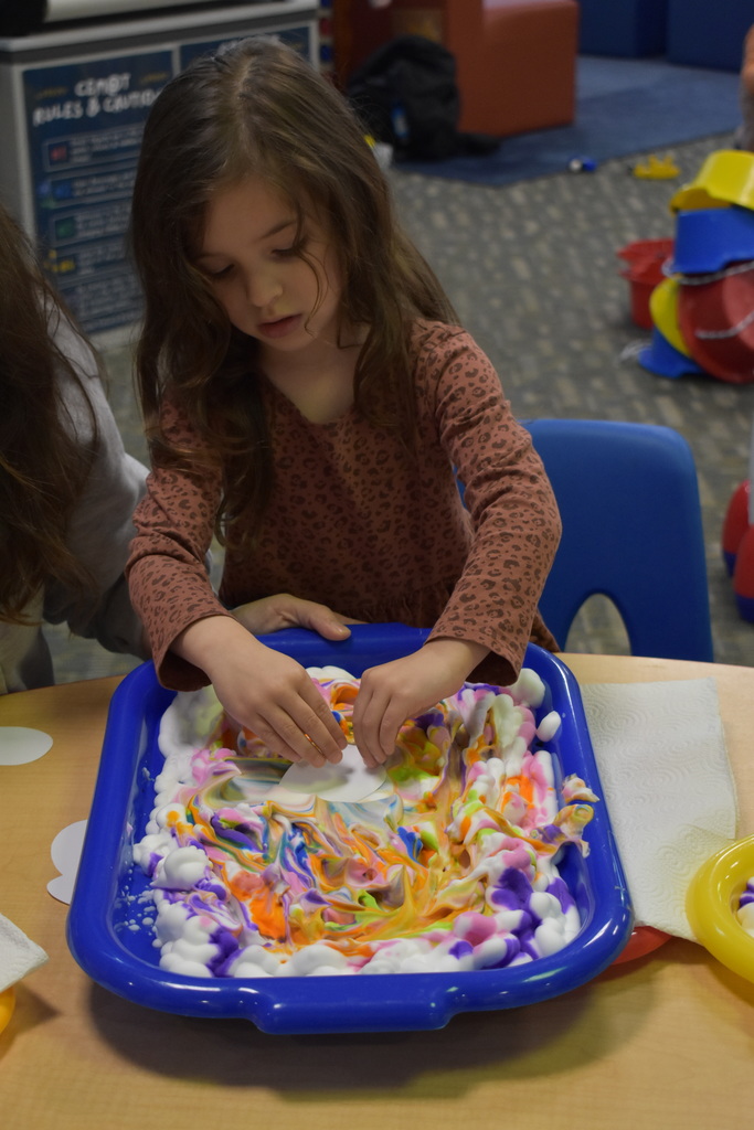 A little girl dying her egg