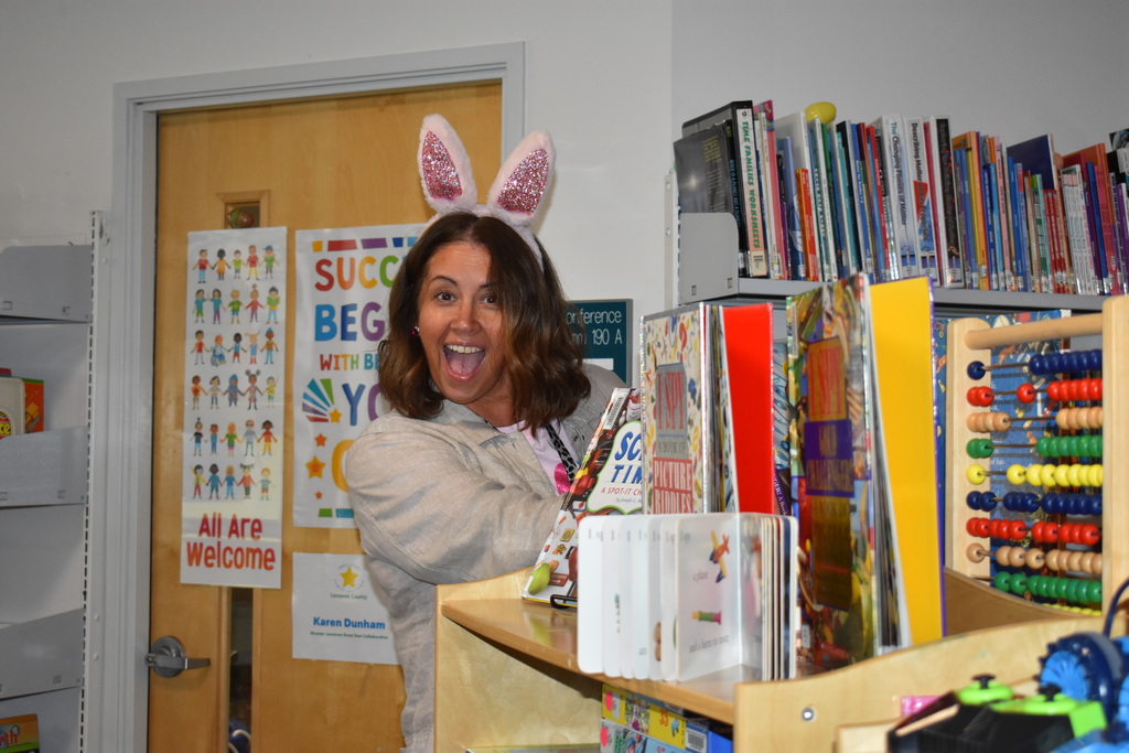 A staff member searching for eggs and smiling at the camera