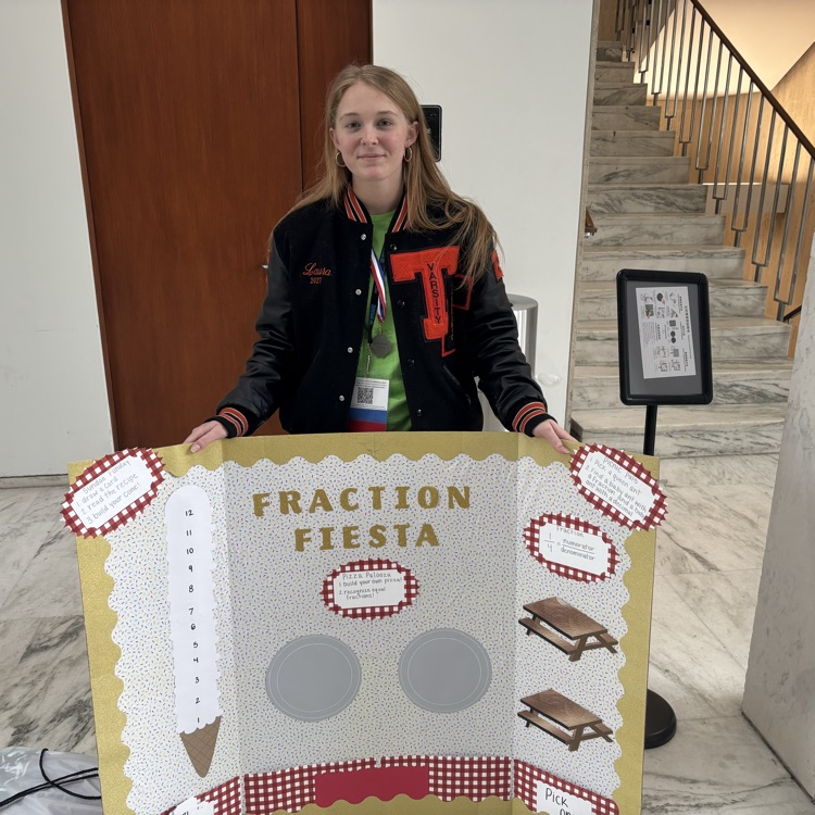 A student standing with her assignment for the contest