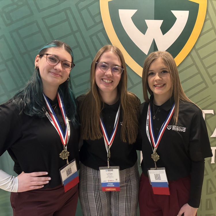 three students posing and smiling for the camera 