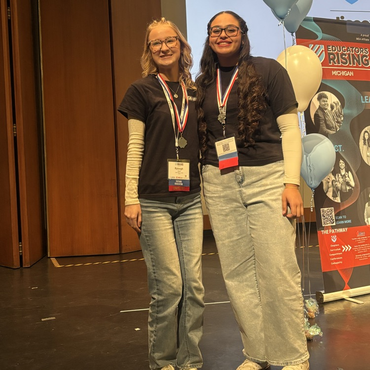 Two students posing on stage and smiling