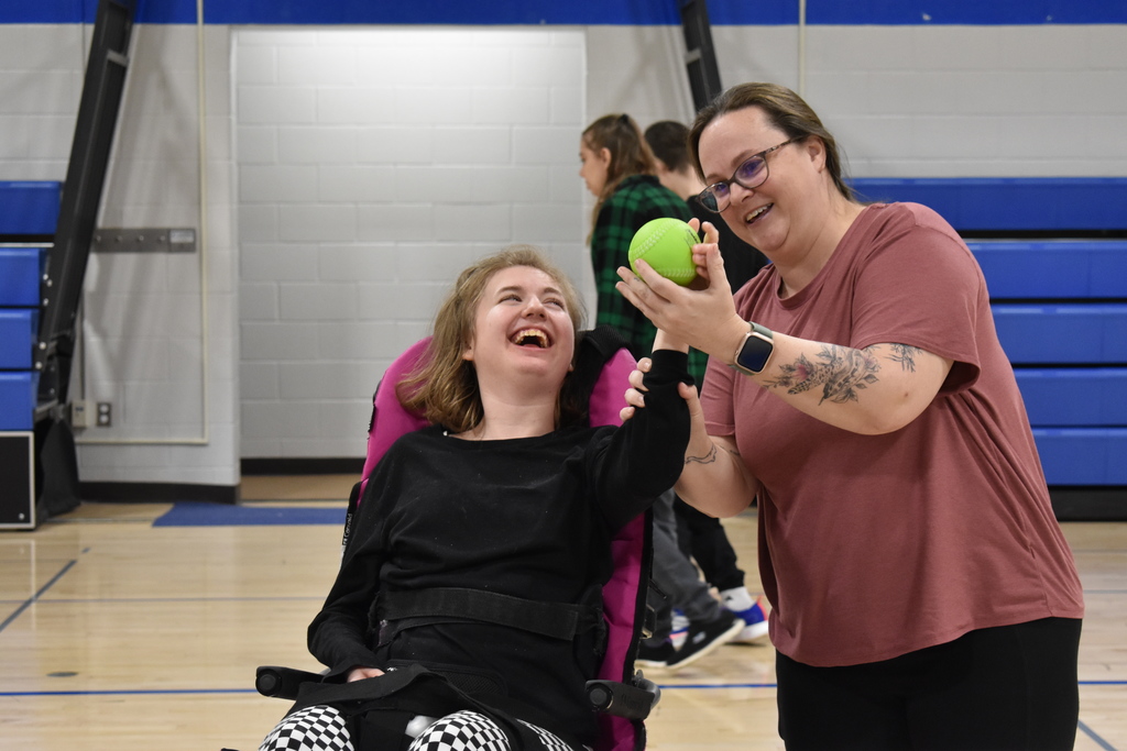 A student smiling at her teacher while she grabs ahold of a ball