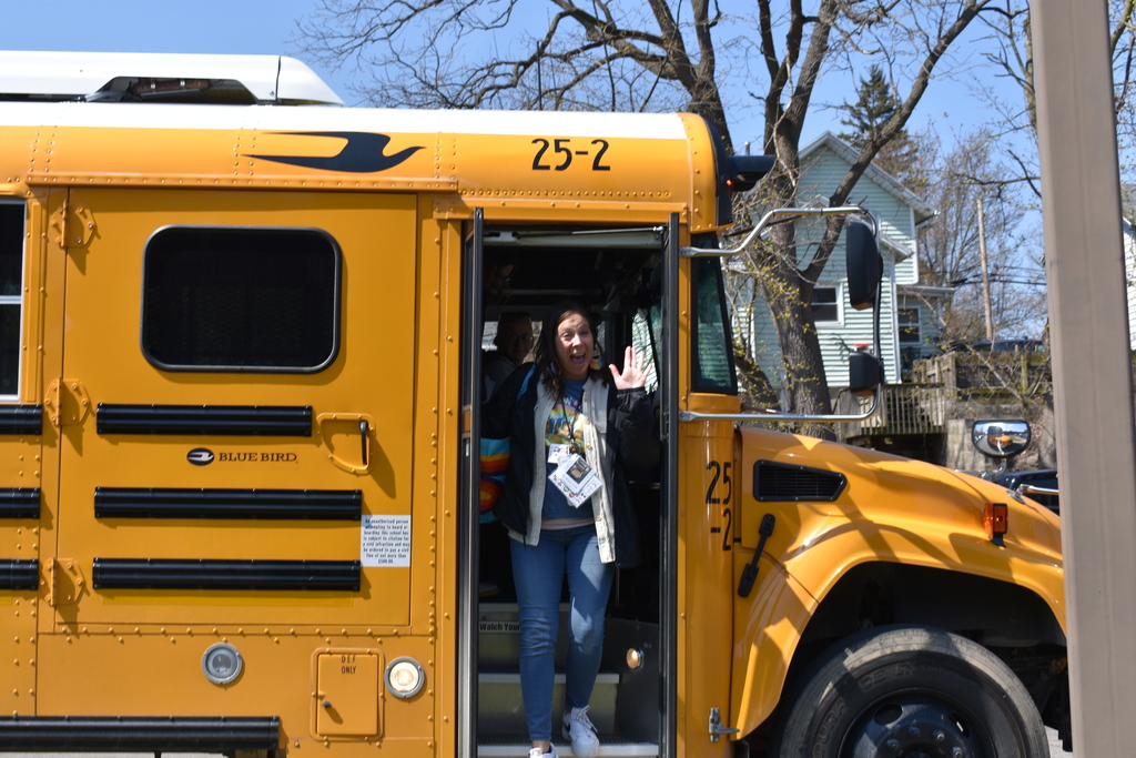 A teacher energetically exiting the bus at the bowling alley