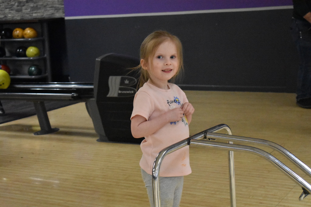 A student smiling after releasing her bowling ball
