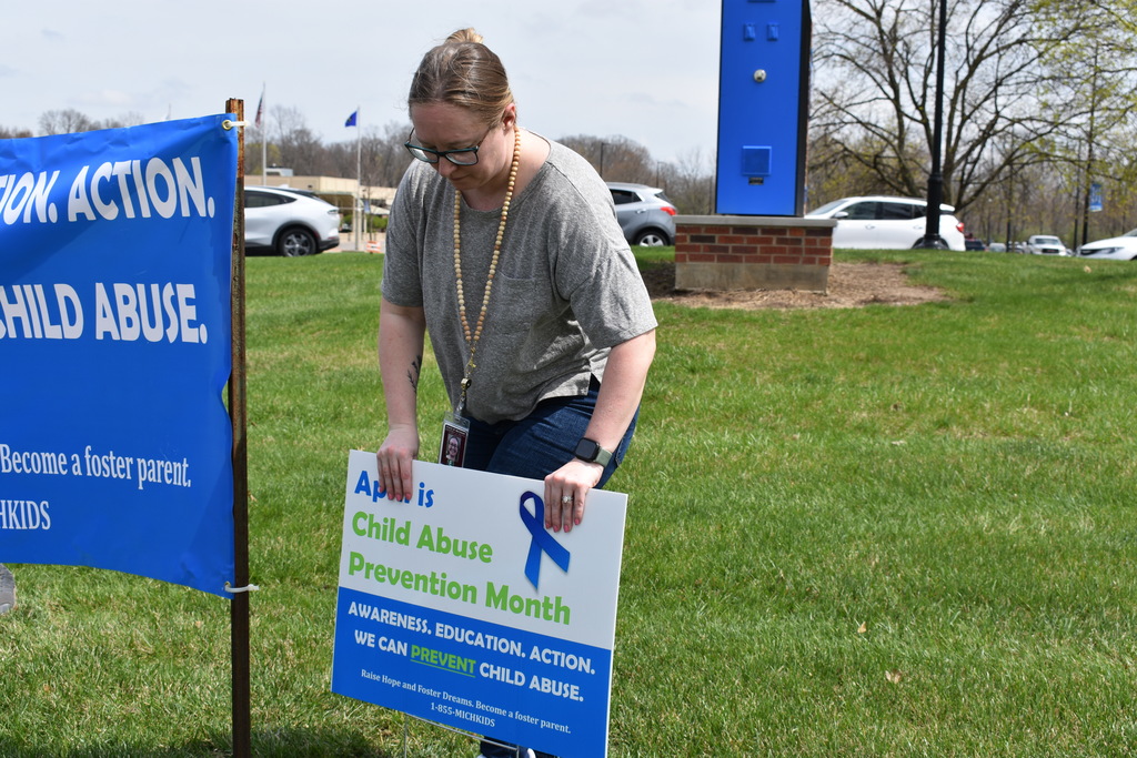 A woman placing a sign in the ground