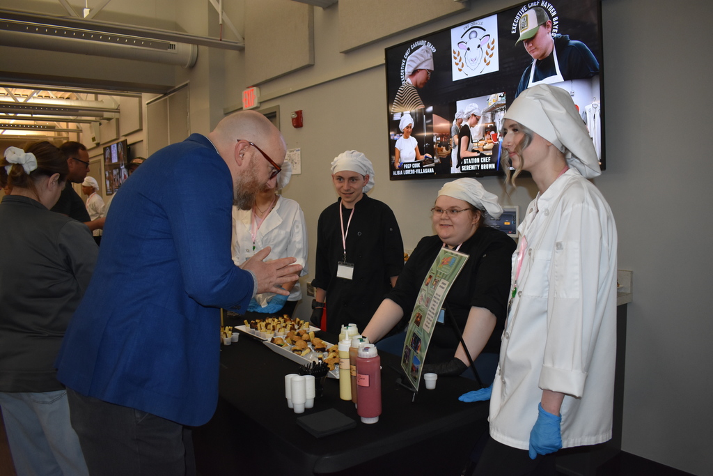 Principal Murray getting a food item while the team explains their product