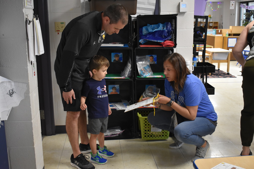 A teacher explaining something to a parent and child