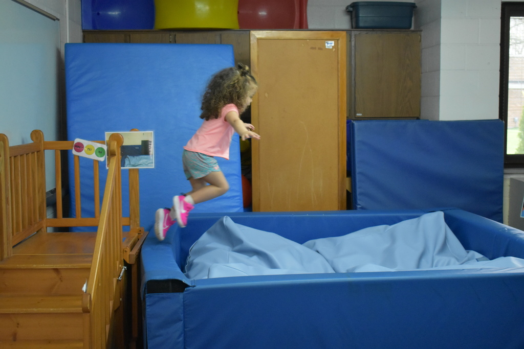 A little girl jumping into a pit 