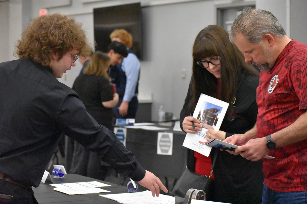A student showing two employers his work