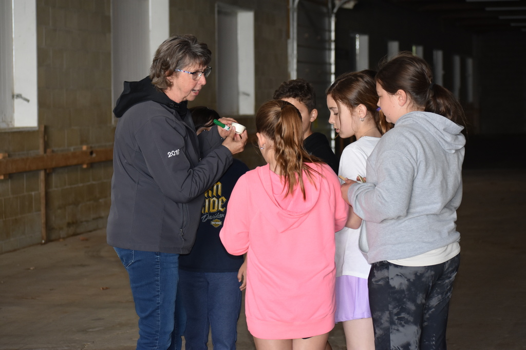 Students learning about how to make butter huddled around a volunteer