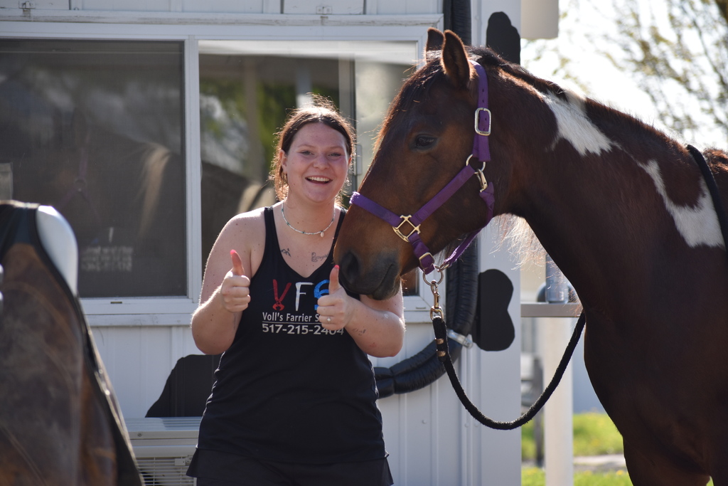 A volunteer giving the thumbs up as she hold her horse's harness