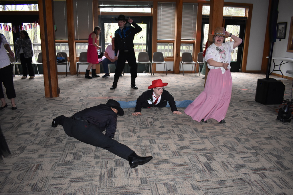 Two students in the splits on the dance floor while others dance around