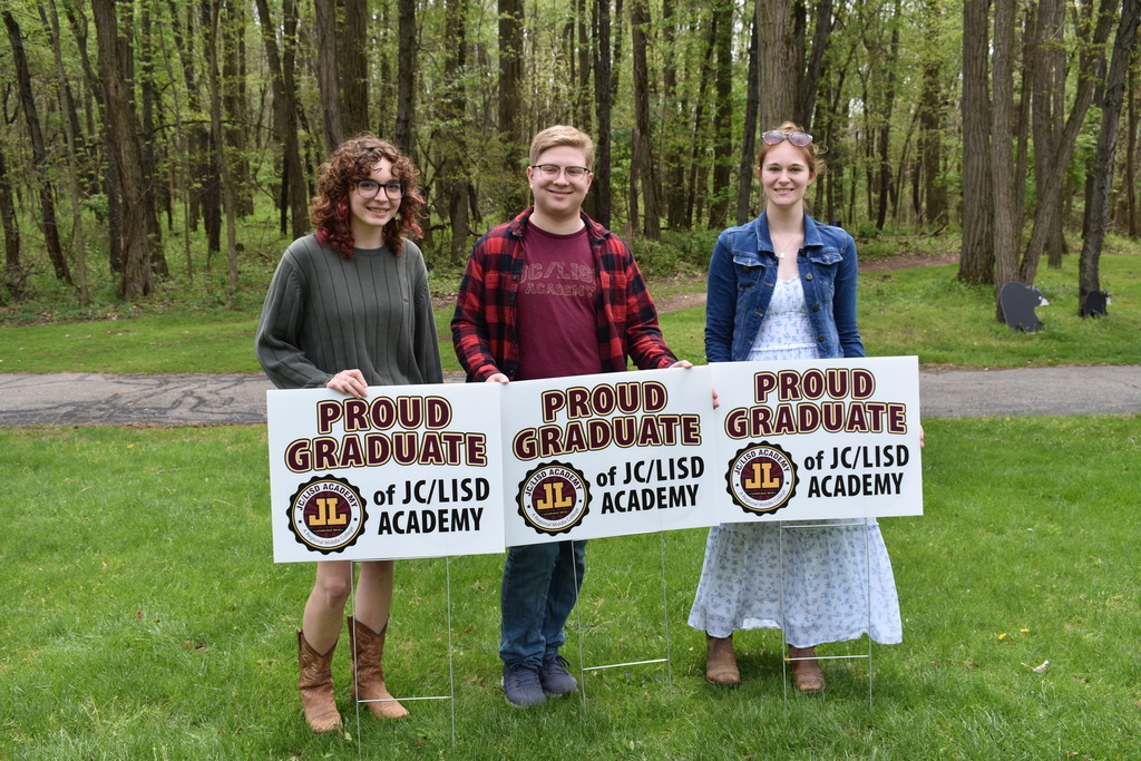 Three students posing with their signs