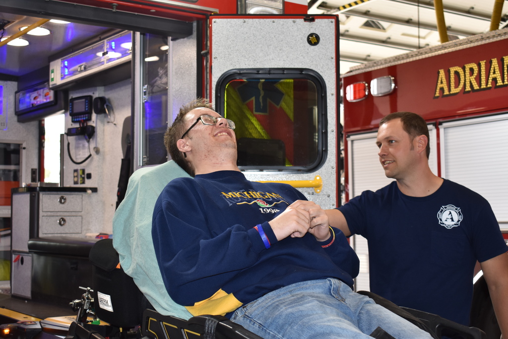 A student acting like a patient while a firefighter puts him in an ambulance
