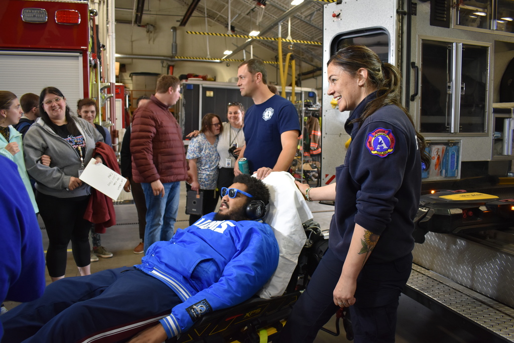 A student being placed on a stretcher while his classmates look on