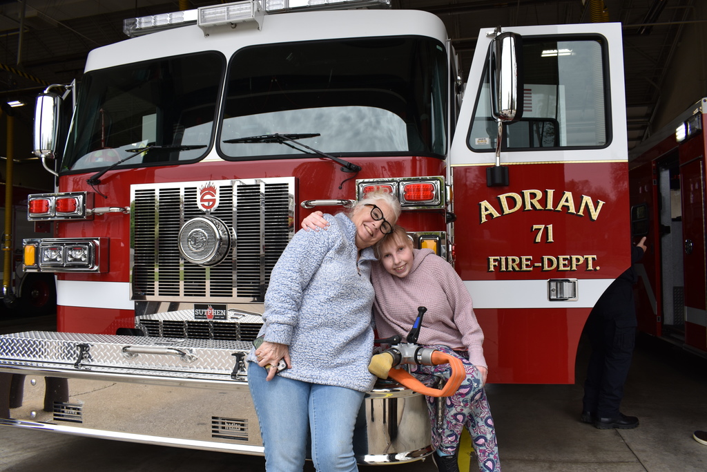 A teacher and student posing in front of a fire truck for a photo