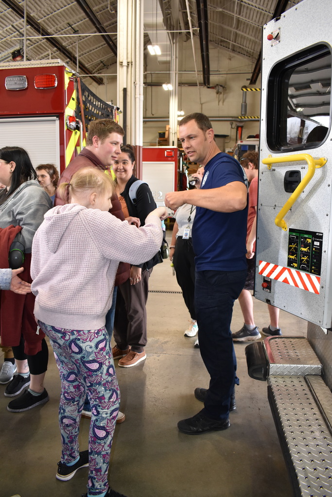 A student giving a firefighter a fist-bump  while others look on