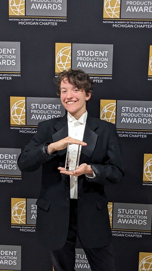 A student posing with his award