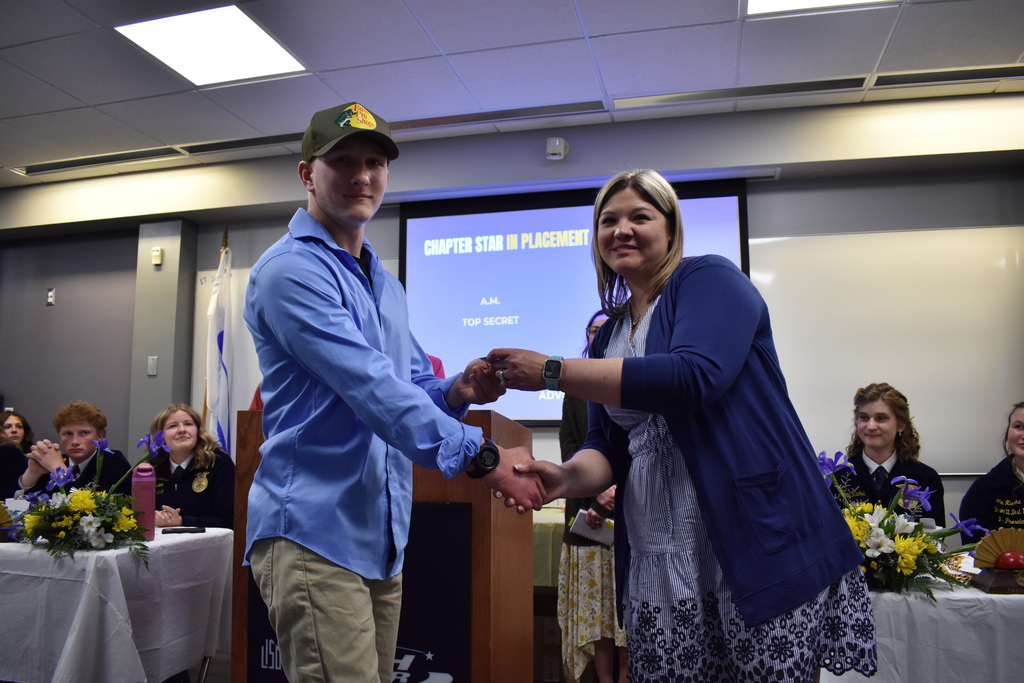 A student receiving an award and shaking the hand of an instructor