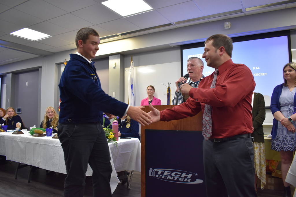 A student receiving an award and shaking the hand of an instructor